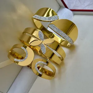 Bracciali rigidi punk in acciaio al titanio dorato con cristalli pavé in una scatola