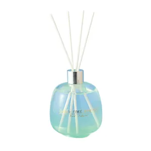 Reed diffuser set with blue gradient glass bottle and white sticks for home fragrance.