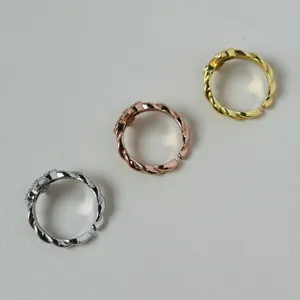 Detailed view of three adjustable twisted clover rings in gold, silver, and rose gold.