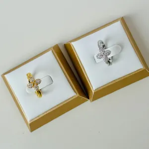 Detail of twisted gold and silver clover rings with zircon inlay on display boxes.