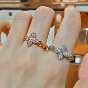 Elegant twisted band rings featuring CZ-encrusted four-leaf clover designs in gold and silver.