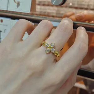 Elegant gold-plated twisted band ring featuring a zircon-encrusted clover flower