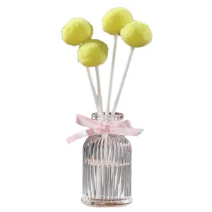 Flameless reed diffuser set with yellow pom pom sticks and glass bottle for home decor.