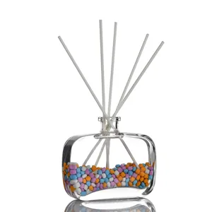 Klares Glas-Raumduft-Fläschchen mit bunten Steinen und weißen Stäbchen für Zuhause.