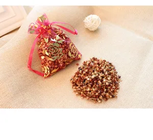 Close-up of natural Xianglingcao grain sachet in pink organza pouch with gold rose pattern.