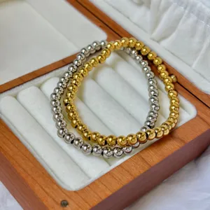Detail view of gold and silver beaded stretch bracelets in a wooden jewelry box.