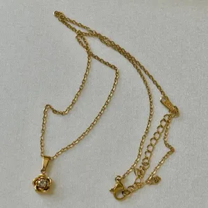 Vue macro détaillée du collier avec pendentif fleur de camélia doré et cristal