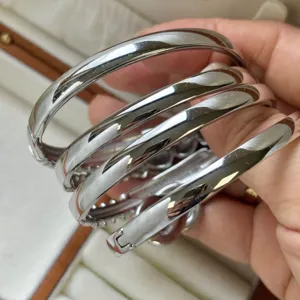 Close-up detail of polished silver-toned stainless steel bangles held in a hand