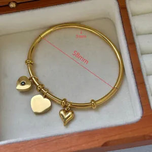Bracciale rigido in acciaio dorato con tre ciondoli a cuore in scatola portagioie in legno