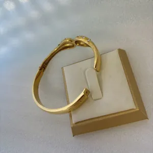 Vue détaillée du bracelet en acier inoxydable doré avec strass sur son présentoir