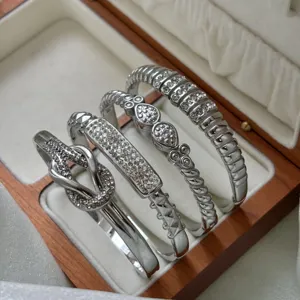 Macro view of four elegant silver stainless steel bangles with crystal pavé in a wooden gift box