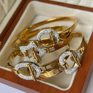 Detailweergave van goudkleurige roestvrijstalen armbanden met kristallen accenten