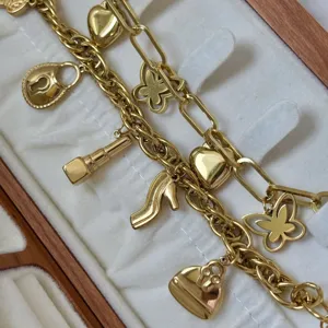 Detailweergave van een vergulde bedelarmband met tas- en vlinderbedels.