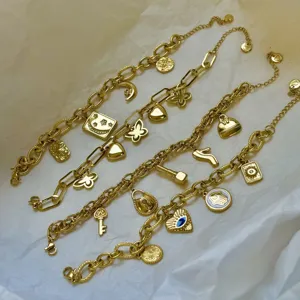 Detailopname van 18K gouden bedelarmbanden met hemelse en hartvormige hangers op witte stof