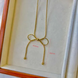 Macro detail view of elegant gold bow necklace showing dimensions of 41mm and 50mm.
