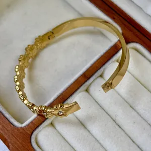 Elegante 18K vergulde roestvrijstalen armband met madeliefjesmotief in een sieradendoos
