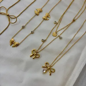 Elegant gold-toned bow necklaces collection on white fabric for a minimalist look.