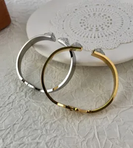 Close-up of gold and silver stainless steel pyramid cuff bracelets with rhinestones.