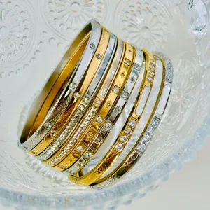 Primo piano di bracciali rigidi in acciaio al titanio da 4 mm impilati con vari zirconi.