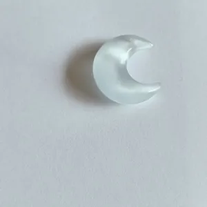 Gros plan d'un pendentif demi-lune en pierre œil-de-chat blanche effet chatoyant