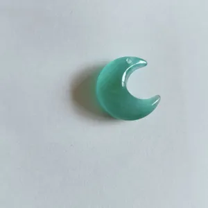 Vue macro d'un pendentif lune en pierre œil de chat turquoise avec effet chatoyance