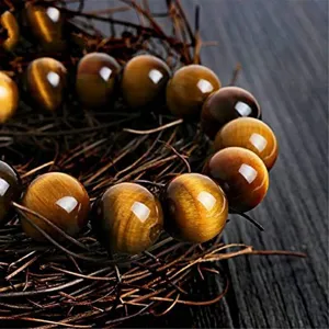 Close-up detail of natural tiger eye gemstone beaded bracelet showcasing chatoyancy in rustic scene