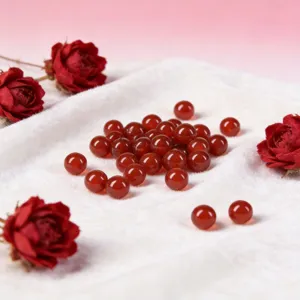 Close-up of natural red agate loose beads displayed on white cloth for DIY jewelry making.