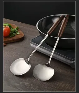 Stainless steel cooking spatula and soup spoon set with wooden handle for home kitchen use.