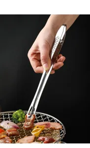 Detail shot of stainless steel barbecue food tong gripping meat on grill, heat resistant.