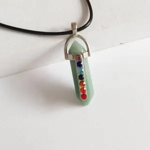 Primer plano de un collar con colgante de pilar hexagonal de cristal verde y piedras chakra.