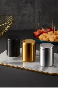 Detail view of sleek stainless steel toothpick holders, modern metal table organizer jars.