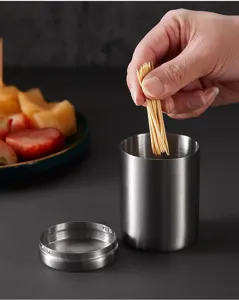 Stainless steel toothpick holder detail view showing container with lid and toothpicks inside.