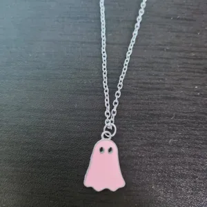 Detailed close-up showing a cute pink enamel ghost pendant on a silver-toned necklace