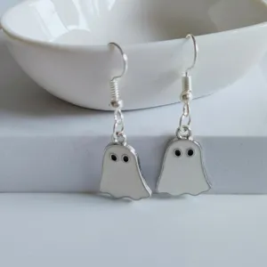 Close-up of cute white enamel ghost earrings with silver hooks for Halloween.