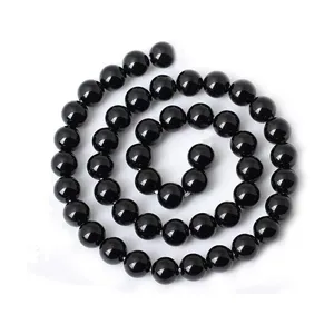 Dettaglio di perline rotonde in vetro nero con superficie liscia per gioielli fai da te.