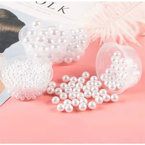Close-up detail of glossy white ABS imitation pearl beads inside small clear containers.