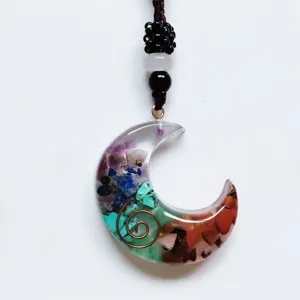 Detail shot of a resin crescent moon pendant filled with colorful crystal chips and copper wire.
