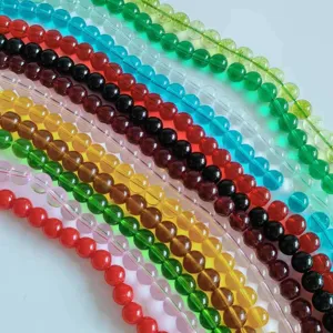 Close-up detail shot of colorful glass round beads strands, assorted translucent DIY jewelry making accessories.
