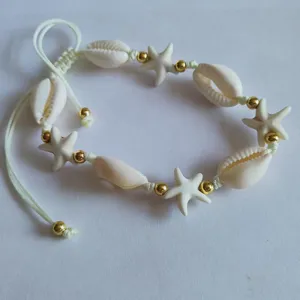 Close-up detail of the handmade beach seashell and starfish bracelet with golden metal beads.