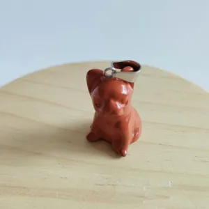 Primo piano di un ciondolo a forma di cane in pietra scolpita con gancio per gioielli.