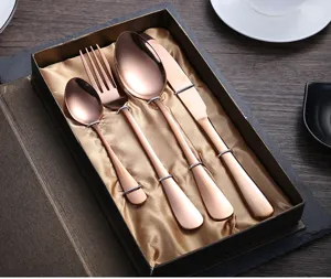 Detalle de cubiertos de acero inoxidable oro rosa, elegante set de cuatro piezas en caja.