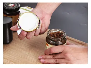 Jar opener tool detail shot showing manual operation on a glass bottle lid for easy kitchen use.