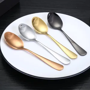 Conjunto de cuatro cucharas de acero inoxidable en varios colores sobre un plato blanco.