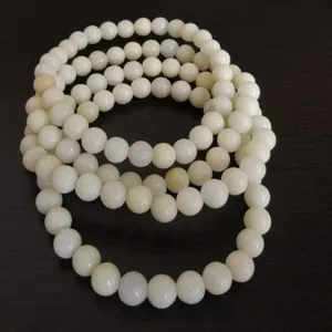 Detailed shot of white natural stone beaded bracelet, smooth round beads, multi-layer style.