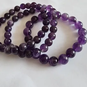Close-up detail of natural purple amethyst crystal round bead bracelets, elegant gemstone texture.