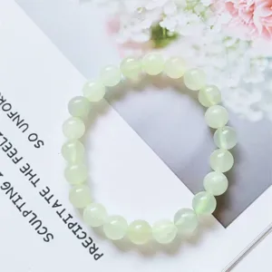 Close-up detail of light green natural stone beaded bracelet, smooth and translucent gemstone.