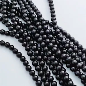 Primo piano dettagliato di perle rotonde in agata nera lucida e ossidiana per gioielli fai da te.