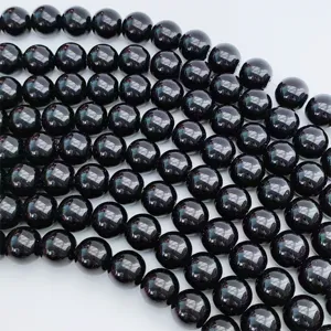 Primo piano dettagliato di perle rotonde in pietra preziosa nera lucida per gioielli fai da te.