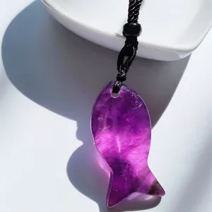 Purple crystal fish pendant detail showing translucent texture and black braided rope.