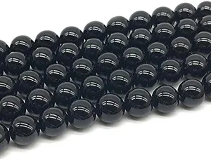 Primo piano dettagliato di perline tonde in ossidiana nera liscia per accessori di gioielli DIY.